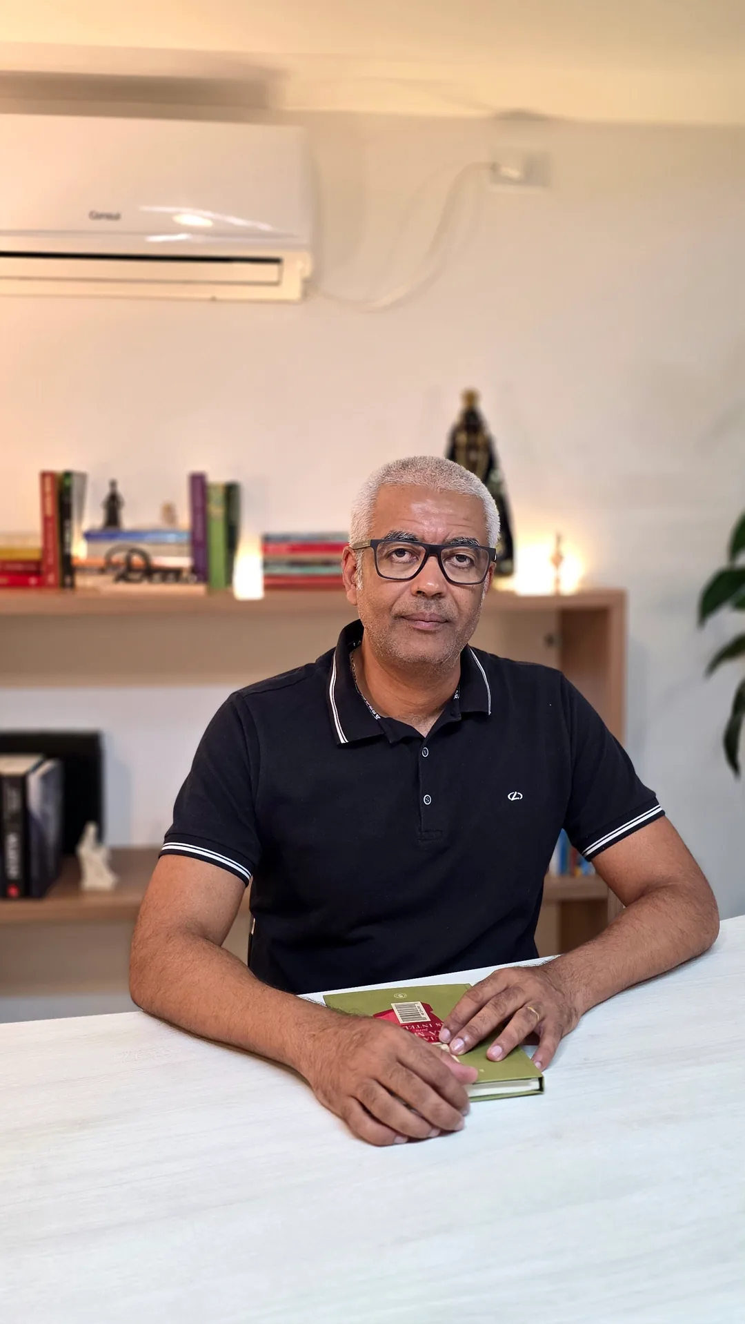 Professor Adriano lendo um livro à mesa